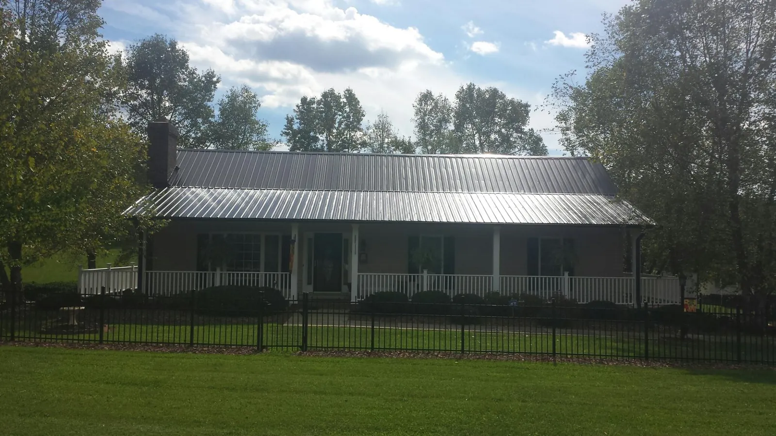 Gray metal roof on a brick ranch with a full width front porch — Gutter Guard Installation work by our crew in Porter