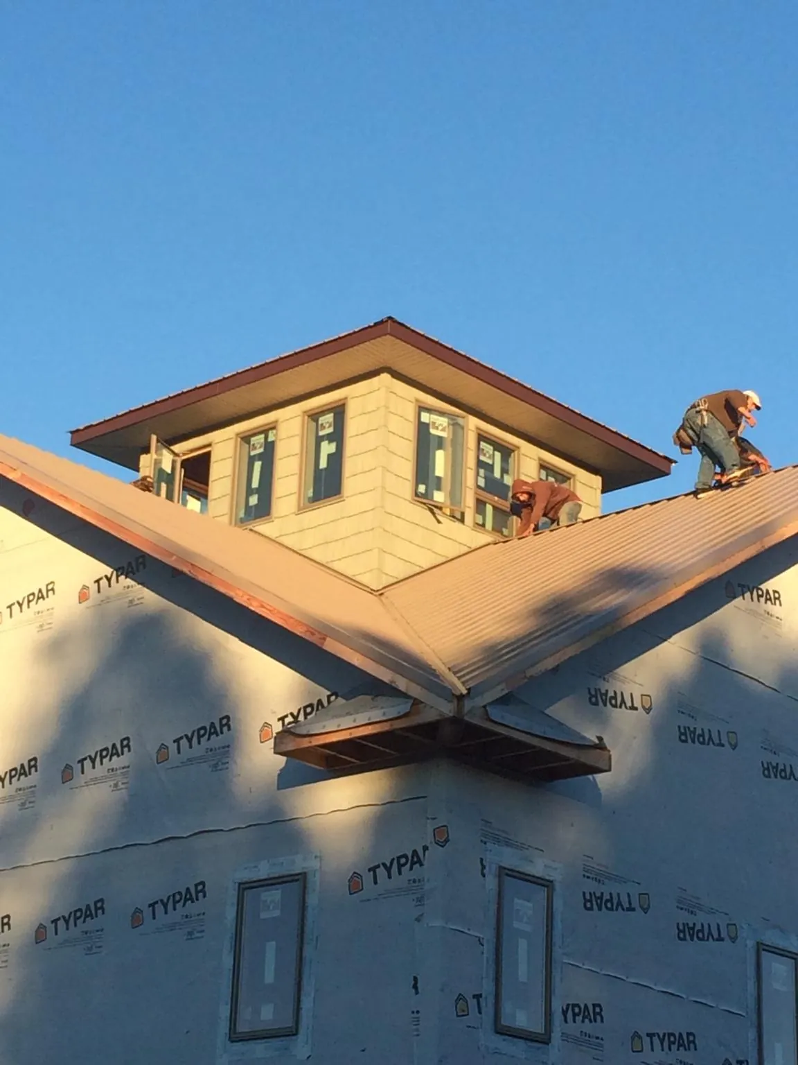 Roofers working around a rooftop cupola on a new metal roof at sunset — Roof Waterproofing in Porter by Roofing Brothers